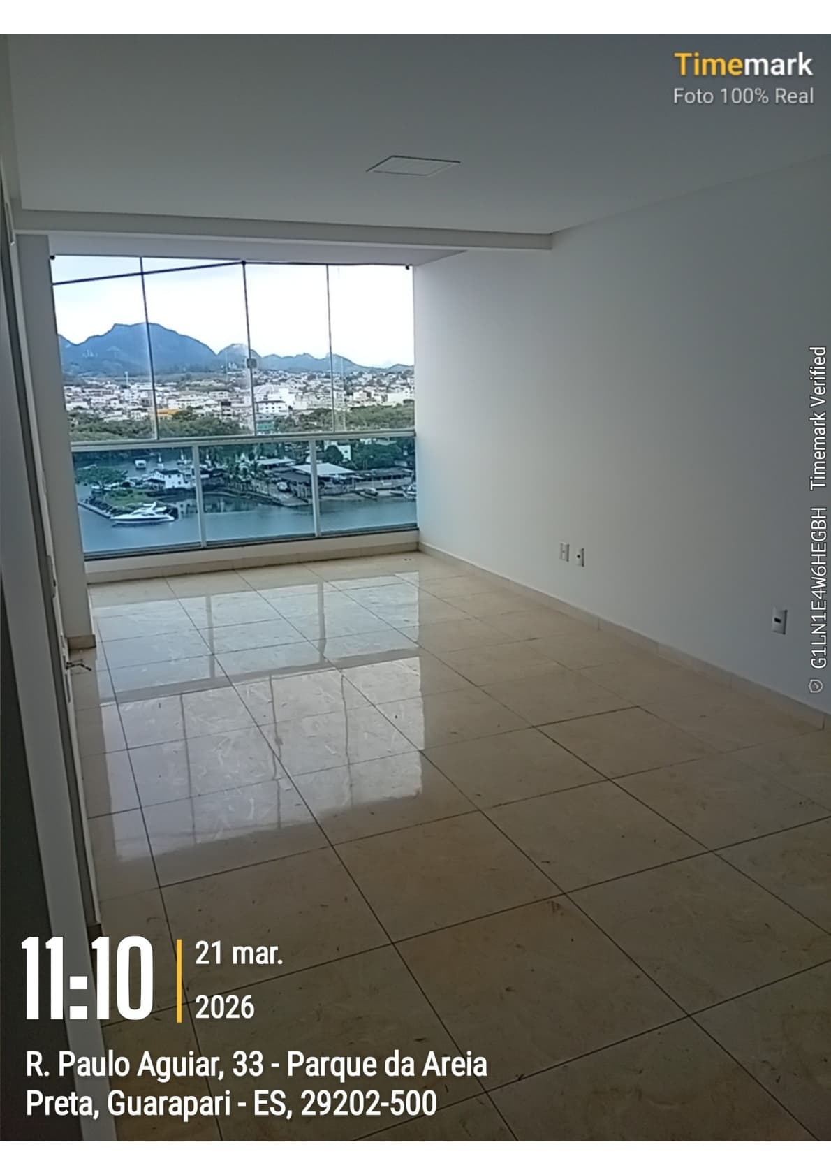 Sala vazia com piso em cerâmica clara e janela ampla com vista para o rio e montanhas